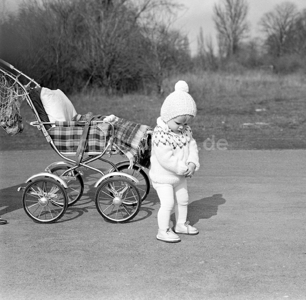 DDR-Fotoarchiv: Magdeburg - Kleines Kind mit Pudelmütze steht am Kinderwagen in Magdeburg