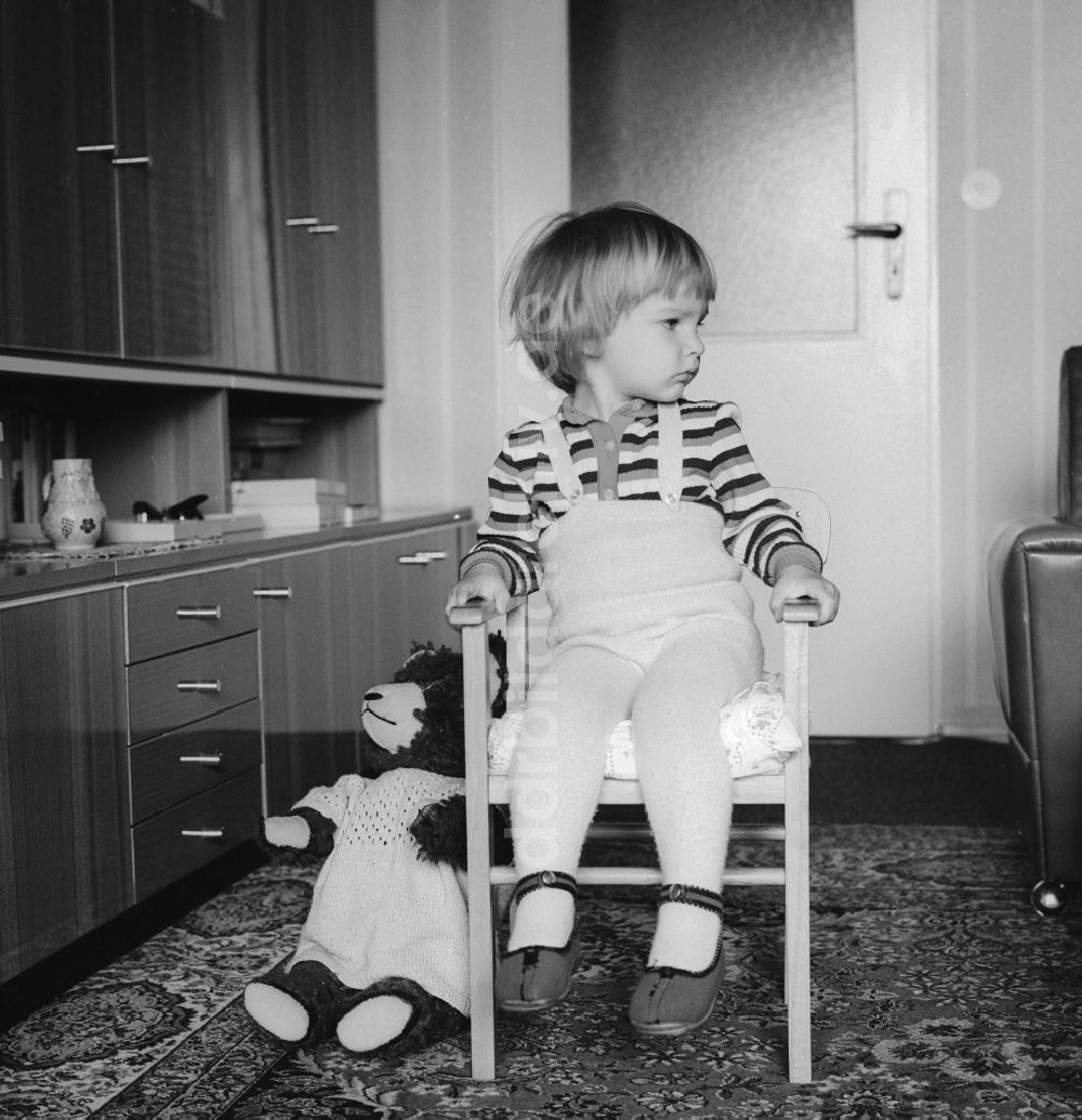 DDR-Bildarchiv: Berlin - Kleines Kind sitzt verträumt auf einem Stuhl in Berlin