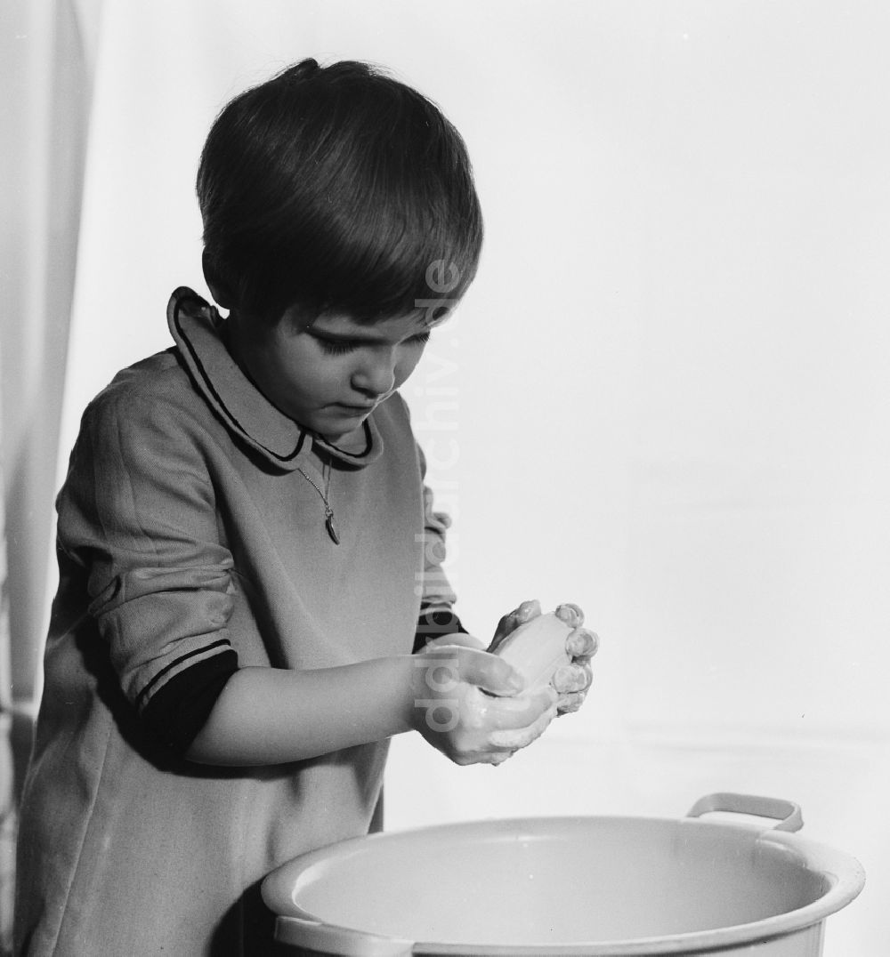 Berlin: Kleines Mädchen beim Hände waschen über einer Plastikschüssel in Berlin