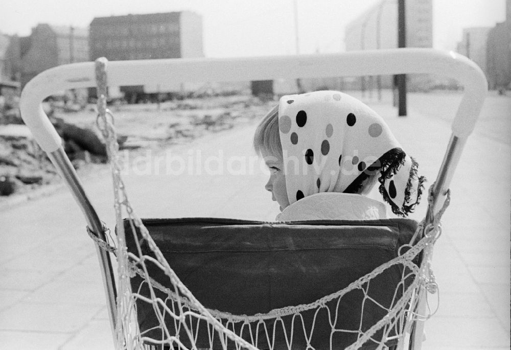 Berlin: Kleines Mädchen mit Kopftuch sitzt in einem Kinderwagen in Berlin, der ehemaligen Hauptstadt der DDR, Deutsche Demokratische Republik