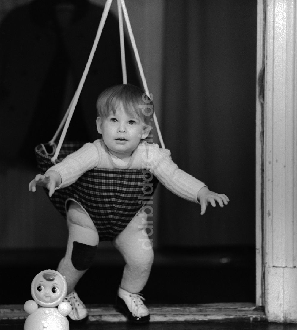 Berlin: Kleinkind in einer Babyschaukel die in einem Türrahmen befestigt ist in Berlin