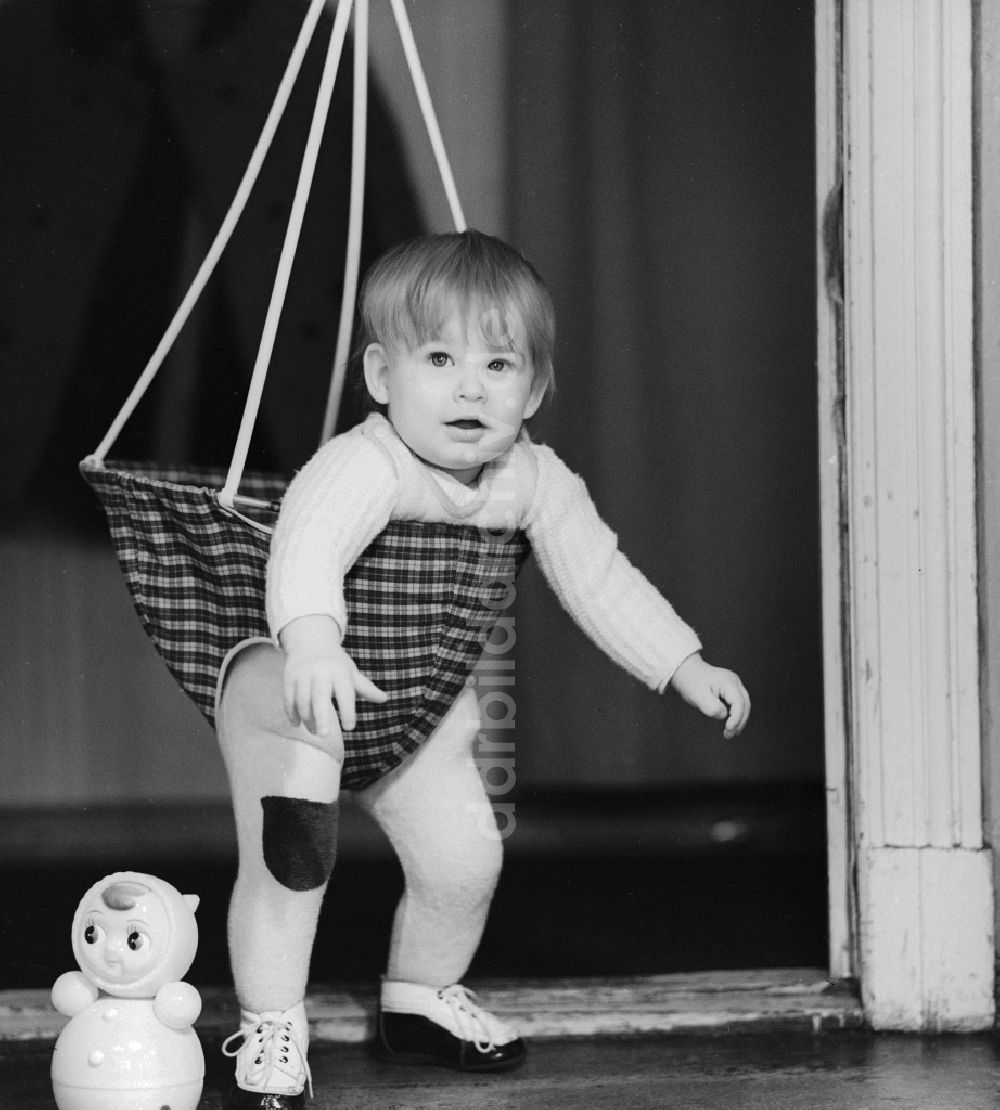 DDR-Bildarchiv: Berlin - Kleinkind in einer Babyschaukel die in einem Türrahmen befestigt ist in Berlin