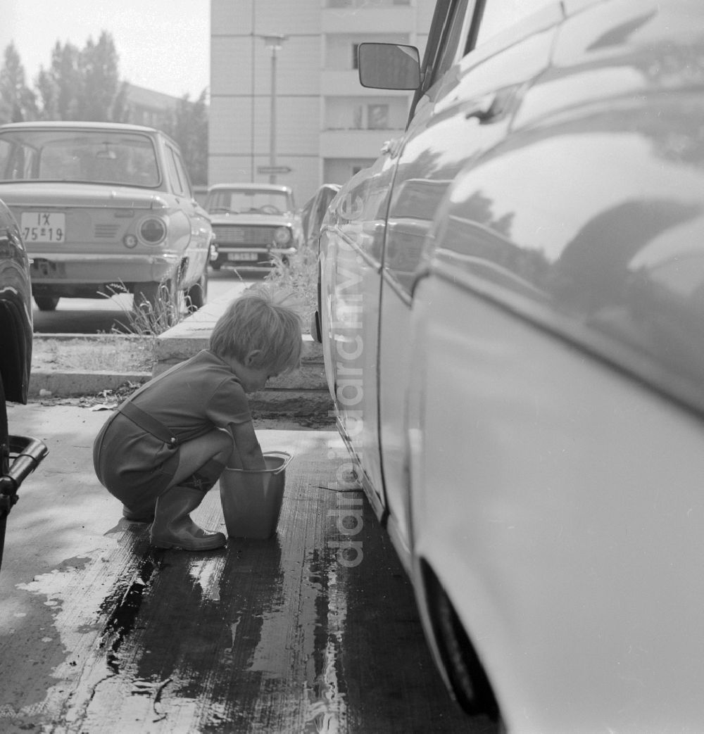 DDR-Fotoarchiv: Berlin - Kleinkind beim Auto waschen auf einem Parkplatz in Berlin, der ehemaligen Hauptstadt der DDR, Deutsche Demokratische Republik