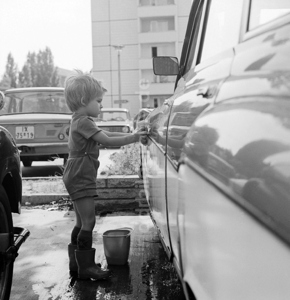 Berlin: Kleinkind beim Auto waschen auf einem Parkplatz in Berlin, der ehemaligen Hauptstadt der DDR, Deutsche Demokratische Republik