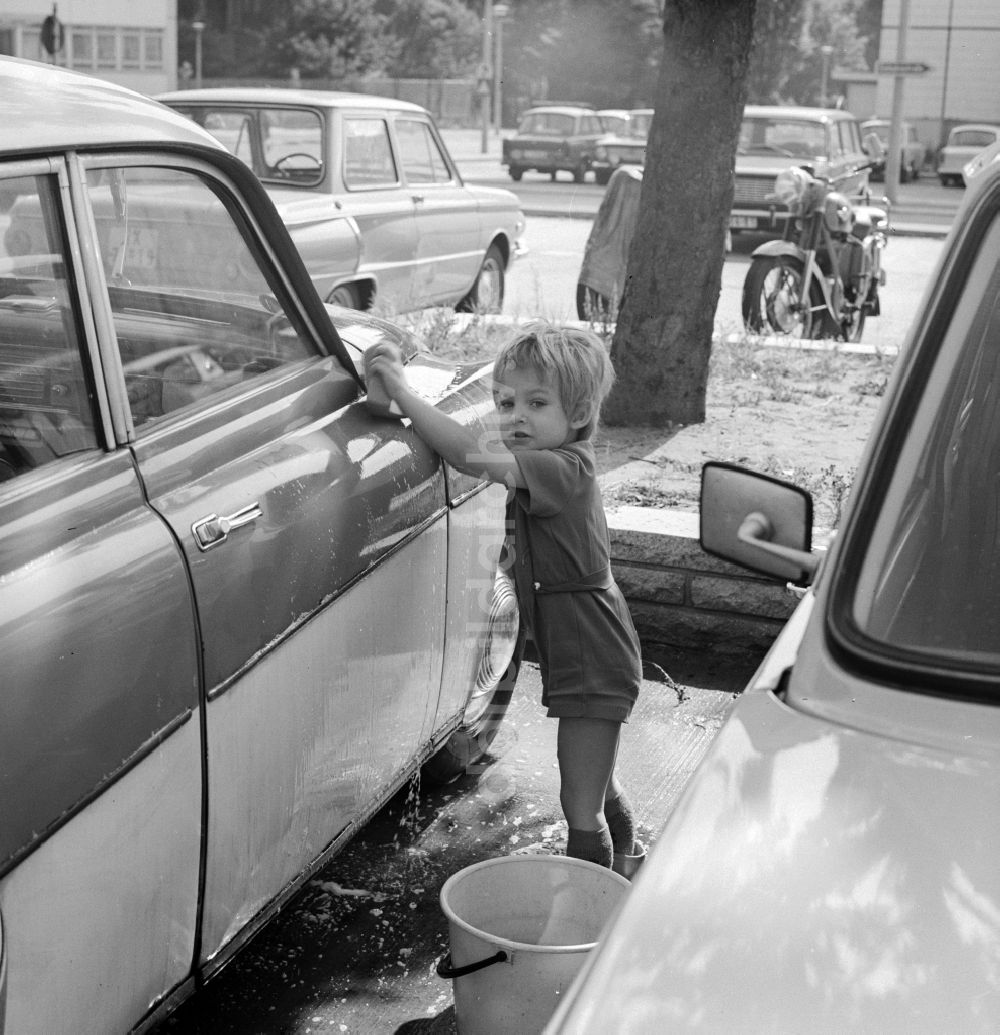 Berlin: Kleinkind beim Auto waschen auf einem Parkplatz in Berlin, der ehemaligen Hauptstadt der DDR, Deutsche Demokratische Republik