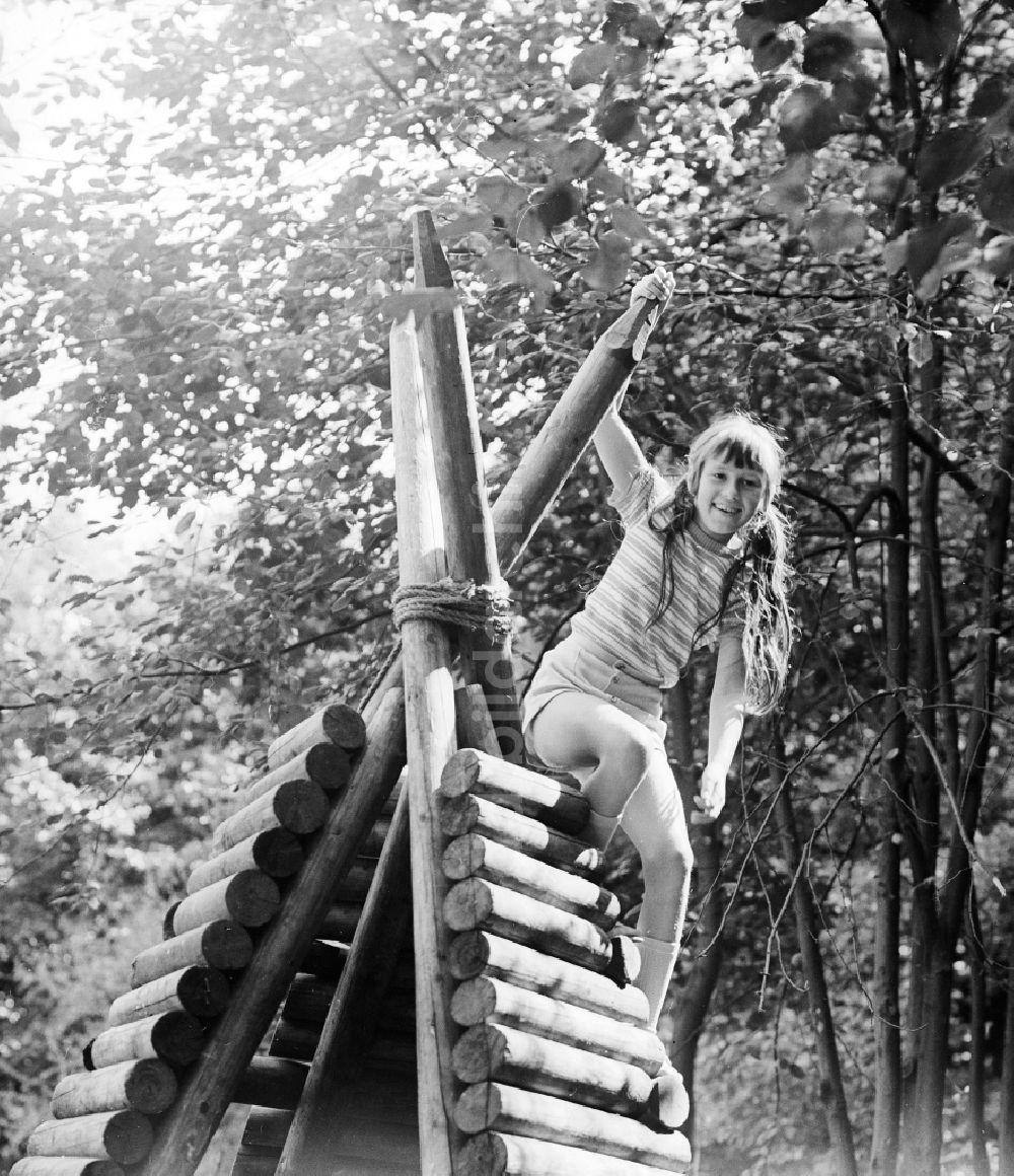 DDR-Bildarchiv: Berlin - Lachendes Mädchen auf einem Holztipi auf einem Spielplatz in Berlin, der ehemaligen Hauptstadt der DDR, Deutsche Demokratische Republik