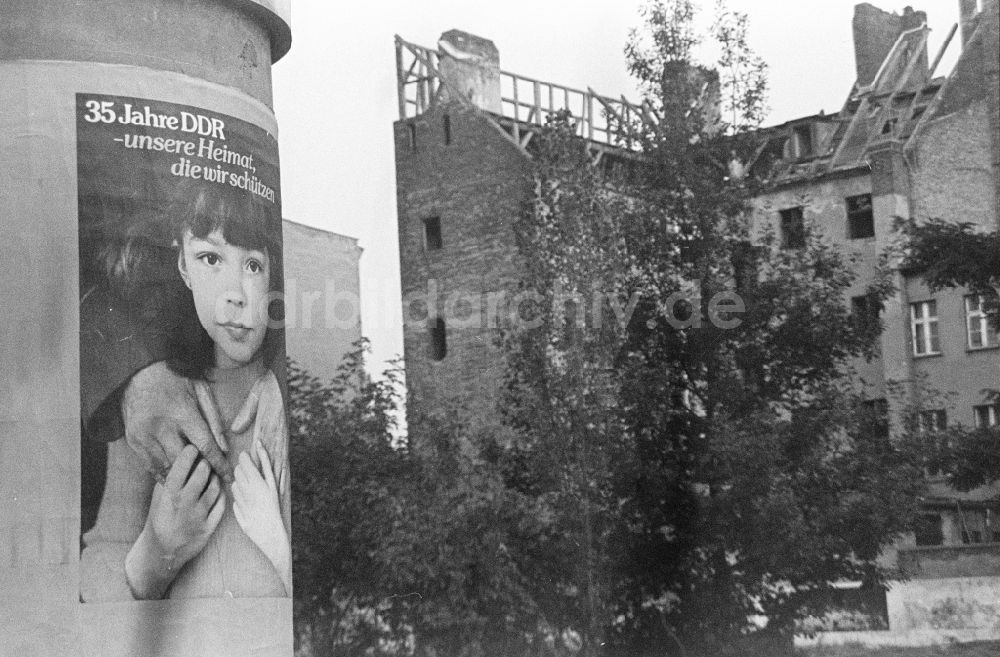 DDR-Fotoarchiv: Berlin - Litfaßsäule als Kontrastprogramm zur verfallenen Wirklichkeit im Altbauwohngebiet am Scheunenviertel in Berlin in der DDR