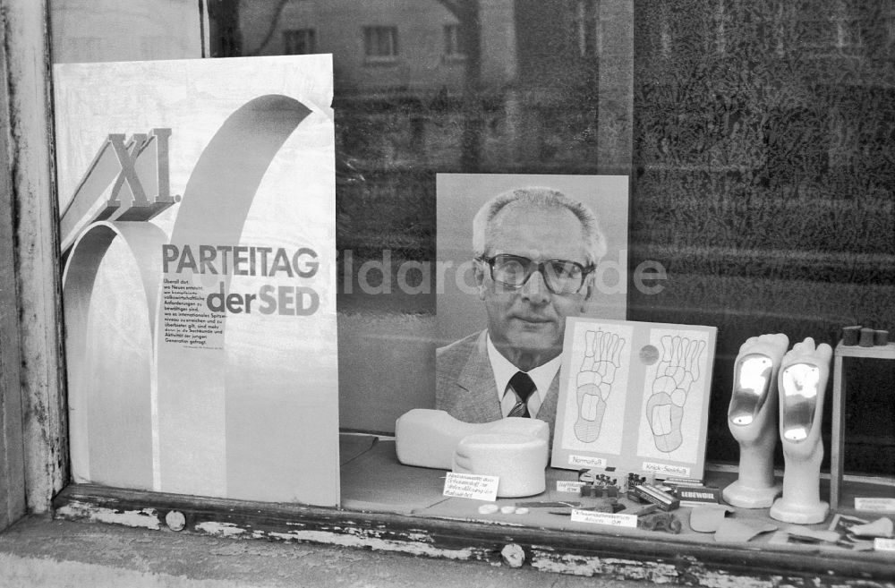 Berlin: Losung und Plakate in einem Schaufenster in Berlin in der DDR
