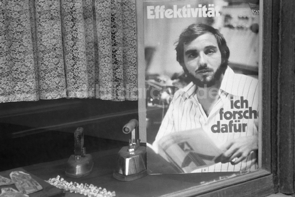 Berlin: Losung und Plakate in einem Schaufenster in Berlin in der DDR