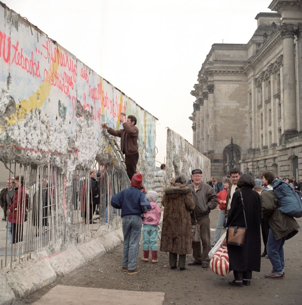 Berlin: Mauerspechte und Souveniersammler an der Berliner Mauer am Reichstagsgebäude in Berlin