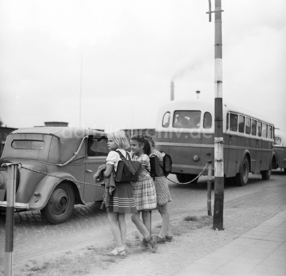 DDR-Fotoarchiv: Schkopau - Mädchen mit Schulranzen stehen am Straßenrand und beobachten den Straßenverkehr in Schkopau in Sachsen-Anhalt in der DDR