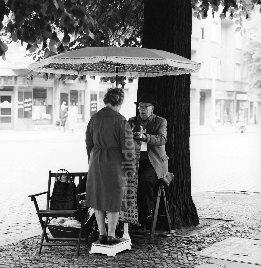 Berlin: Mit Hut und Anzug bekleideter älterer Herr beim wiegen von Straßen- Passanten auf der Schönhauser Allee in Berlin, der ehemaligen Hauptstadt der DDR, Deutsche Demokratische Republik