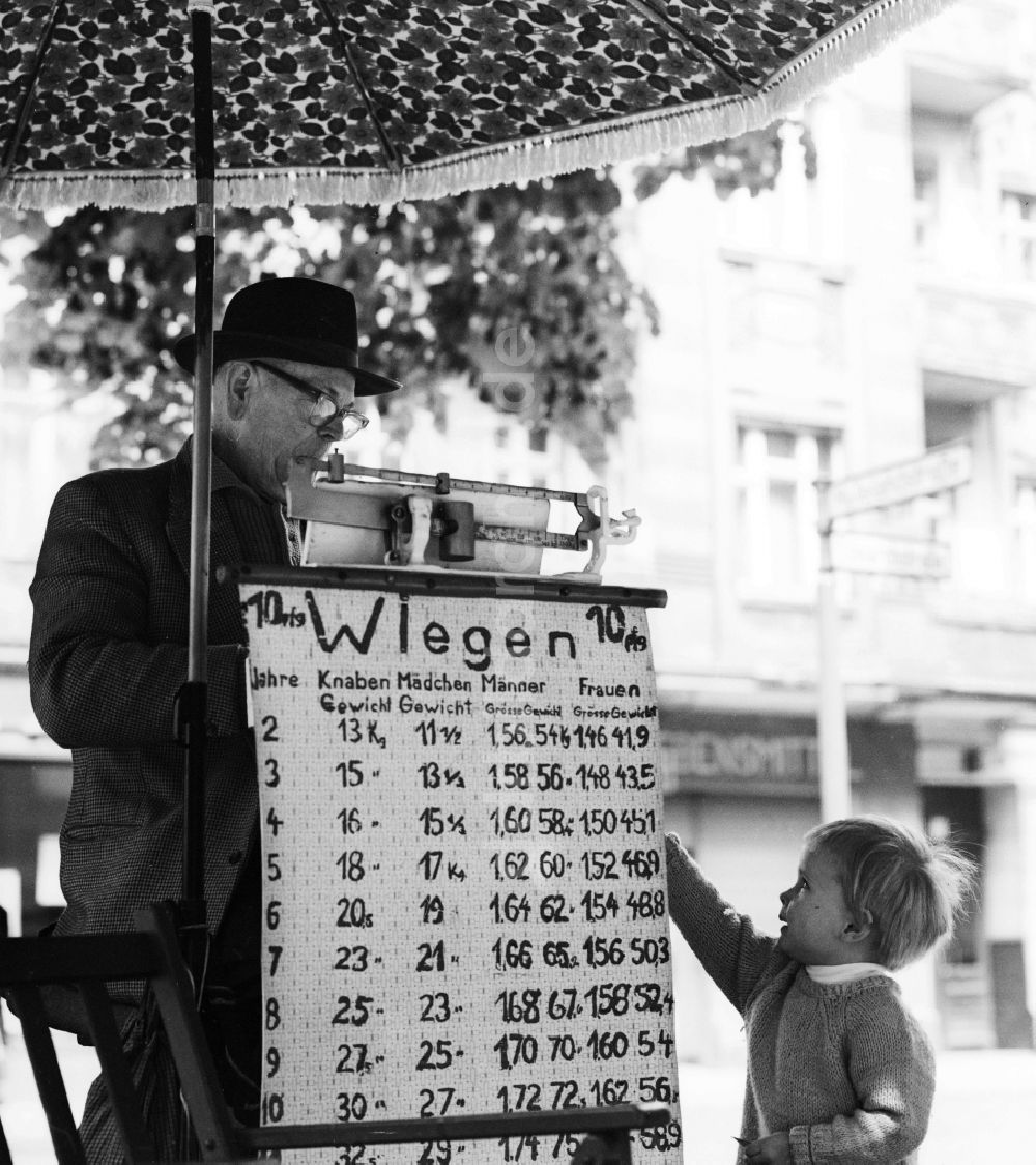 DDR-Fotoarchiv: Berlin - Mit Hut und Anzug bekleideter älterer Herr beim wiegen von Straßen- Passanten auf der Schönhauser Allee in Berlin, der ehemaligen Hauptstadt der DDR, Deutsche Demokratische Republik