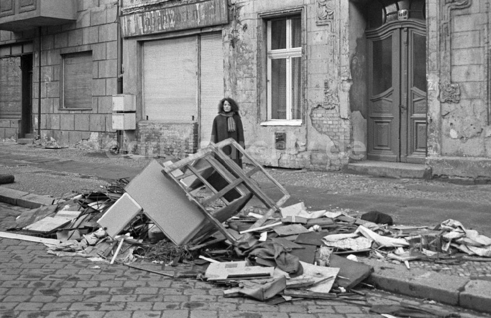 DDR-Fotoarchiv: Berlin - Mode und Kleidung von Straßen- Passanten vor Straßenmüllhaufen in Berlin in der DDR