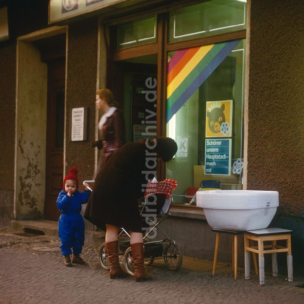 DDR-Bildarchiv: Berlin - Mutter mit Kinderwagen und einem Kleinkind vor einem HO Geschäft für Haushaltswaren in Berlin, der ehemaligen Hauptstadt der DDR, Deutsche Demokratische Republik