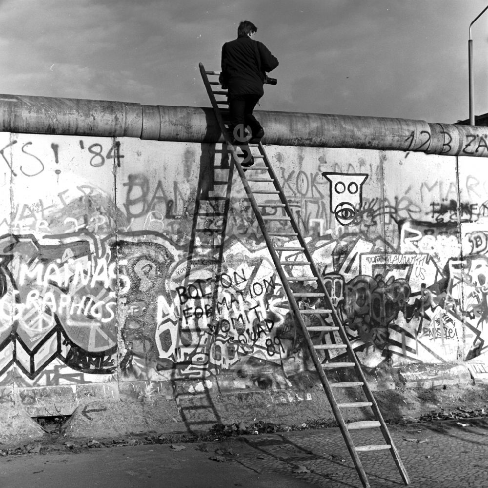 DDR-Fotoarchiv: Berlin - Mitte - Neugierig klettert ein Fotograf auf einer Leiter an der Berliner Mauer empor