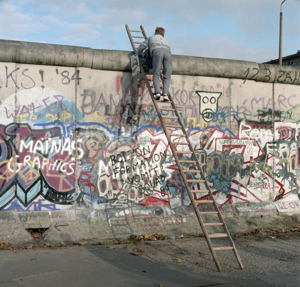 DDR-Fotoarchiv: Berlin - Mitte - Neugieriger Mann klettert mit Hilfe einer Leiter an der Berliner Mauer hoch