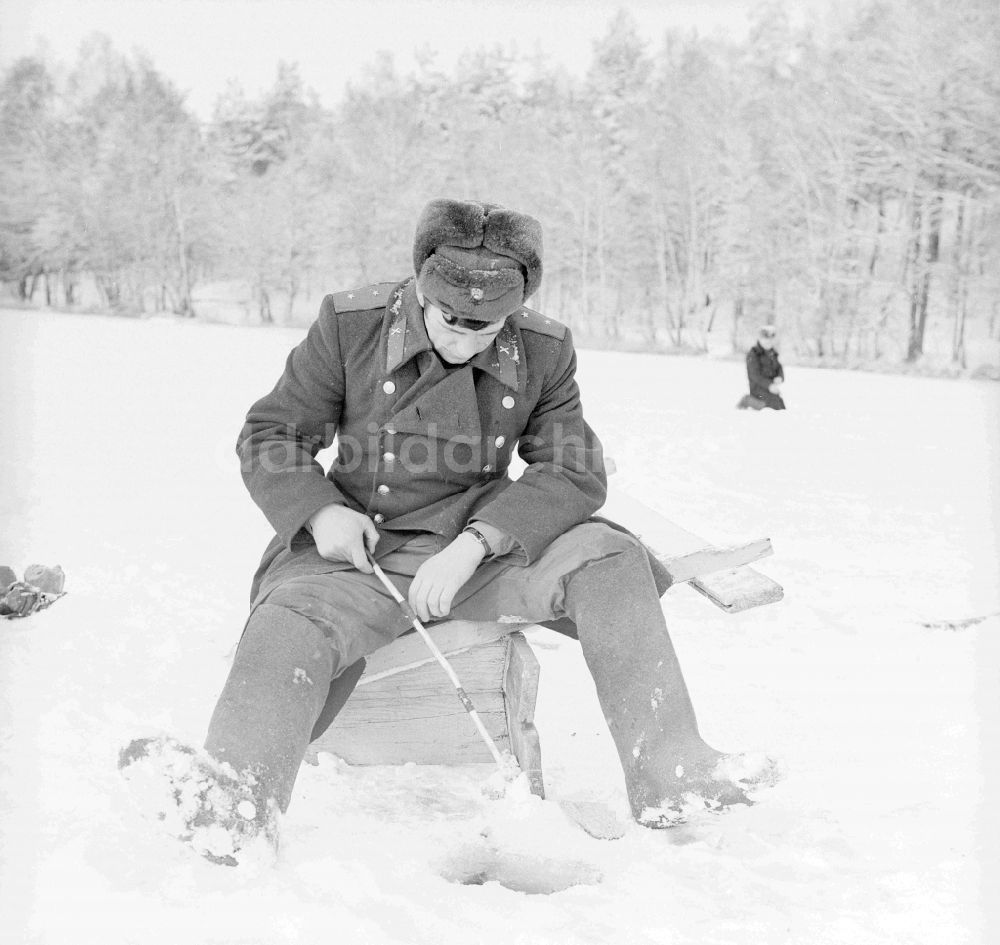 DDR-Fotoarchiv: Wittstock/Dosse - Russischer Soldat in Winteruniform beim Eisangeln auf dem Kleinen Baalsee in Wittstock/Dosse in Brandenburg in der DDR