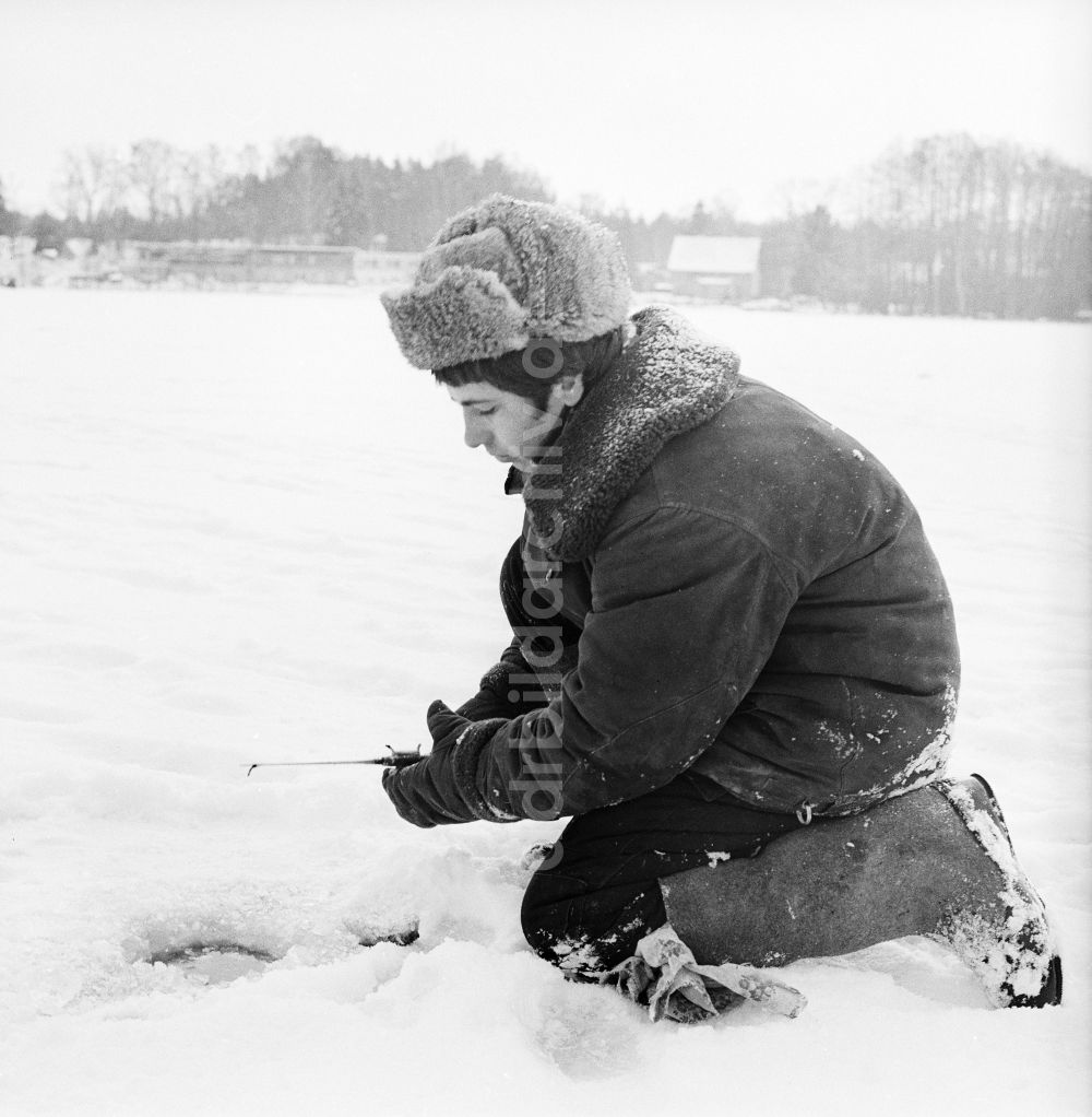 Wittstock/Dosse: Russischer Soldat in Winteruniform beim Eisangeln auf dem Kleinen Baalsee in Wittstock/Dosse in Brandenburg in der DDR