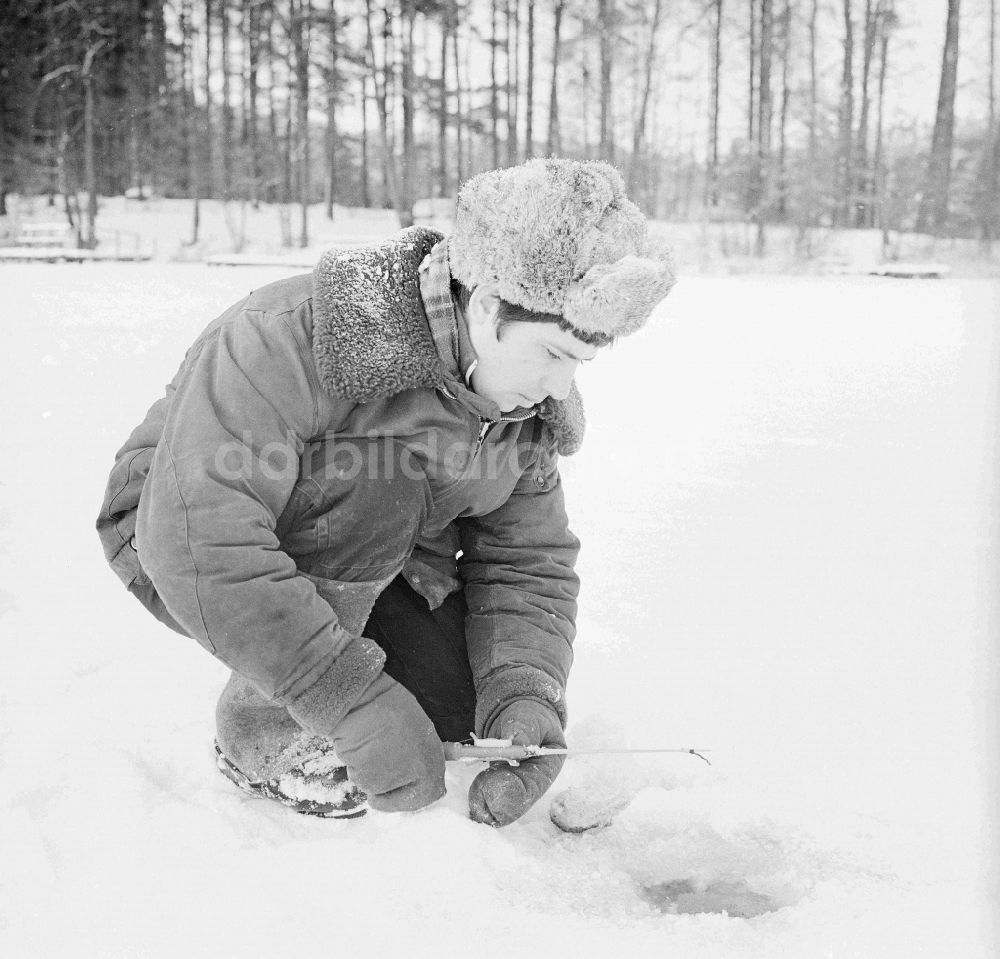DDR-Bildarchiv: Wittstock/Dosse - Russischer Soldat in Winteruniform beim Eisangeln auf dem Kleinen Baalsee in Wittstock/Dosse in Brandenburg in der DDR