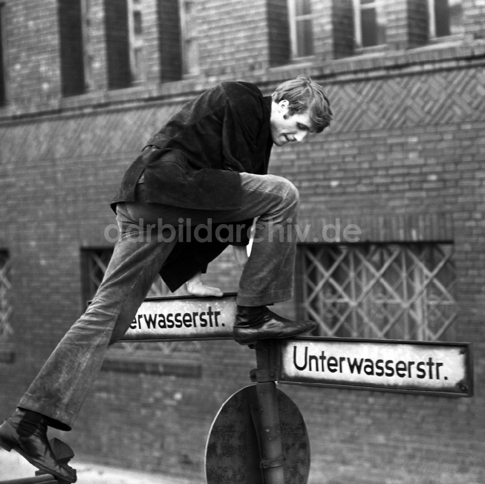 DDR-Fotoarchiv: Berlin - Schauspieler Reiner Schöne klettert auf ein Straßenschild in Ostberlin in der DDR