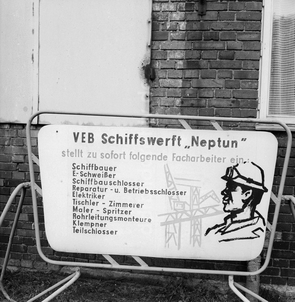 DDR-Fotoarchiv: Rostock - Schild der VEB Schiffswerft Neptun über offene Arbeitsstellen in Rostock in Mecklenburg-Vorpommern in der DDR