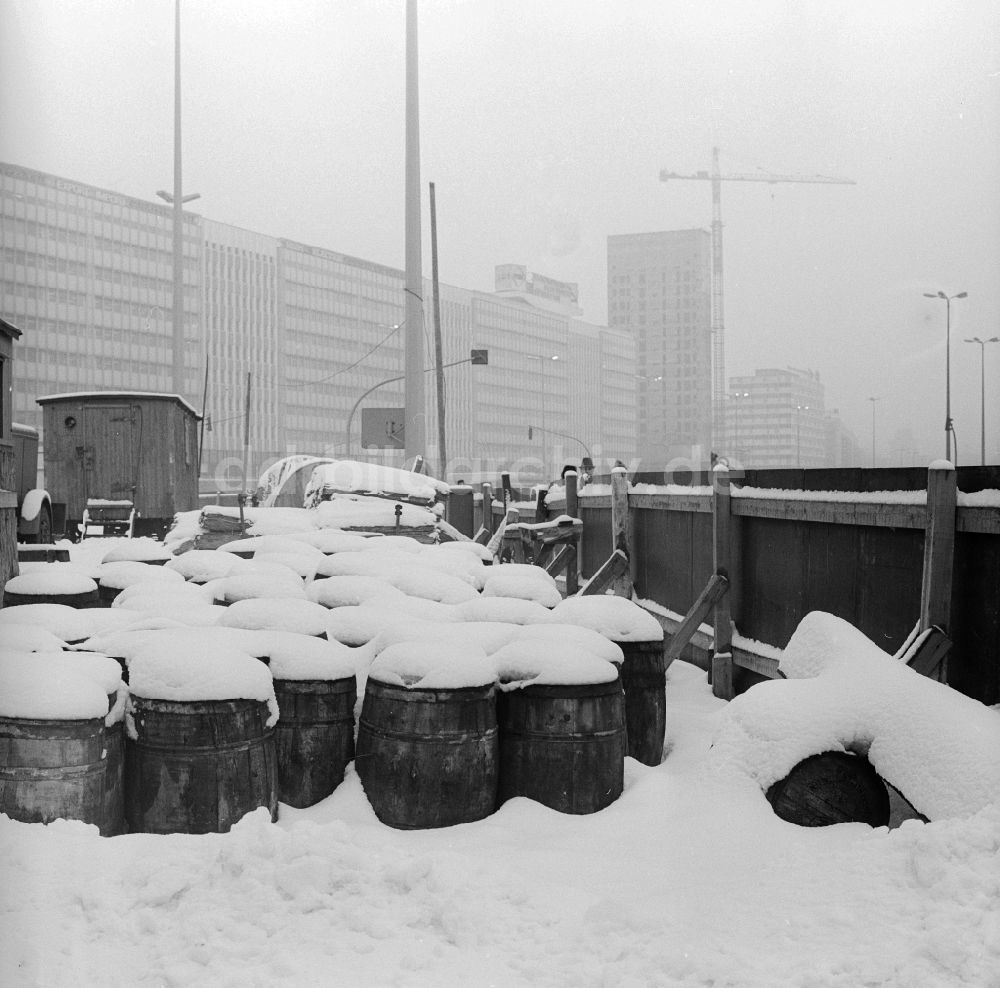 Berlin: Schneebedeckte Fässer auf einer Baustelle in Berlin, der ehemaligen Hauptstadt der DDR, Deutsche Demokratische Republik