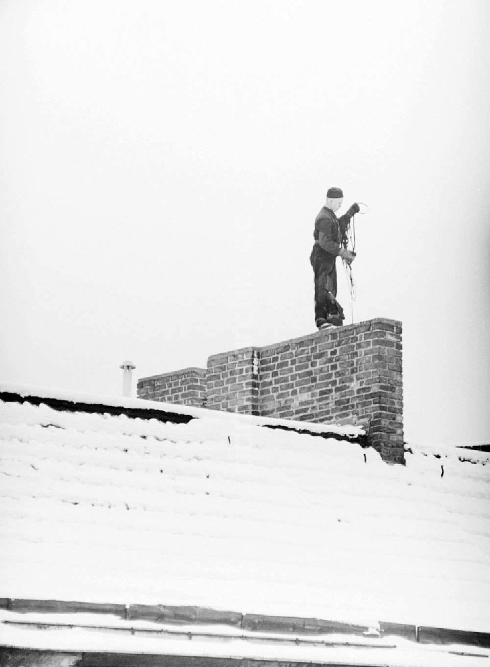 DDR-Fotoarchiv: Berlin - Schornsteinfeger auf schneebedeckten Dächern bei der Arbeit in Berlin, der ehemaligen Hauptstadt der DDR, Deutsche Demokratische Republik
