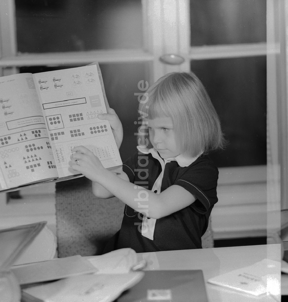 DDR-Fotoarchiv: Berlin - 1. Schultag - Mädchen zeigt stolz ihr erstes Mathebuch in Berlin, der ehemaligen Hauptstadt der DDR, Deutsche Demokratische Republik