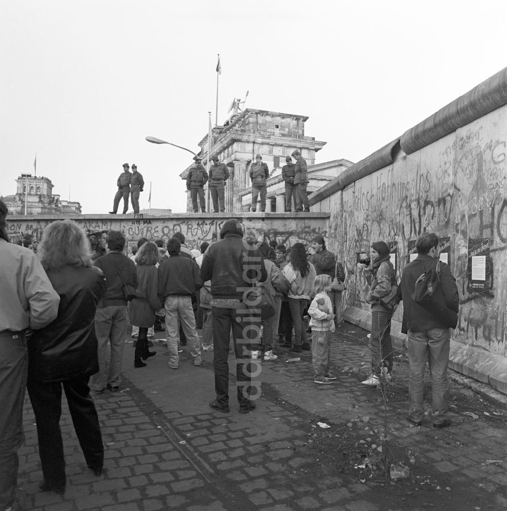 Berlin - Mitte: Soldaten der Grenztruppen der DDR auf der Berliner Mauer vor dem Brandenburger Tor in Berlin - Mitte