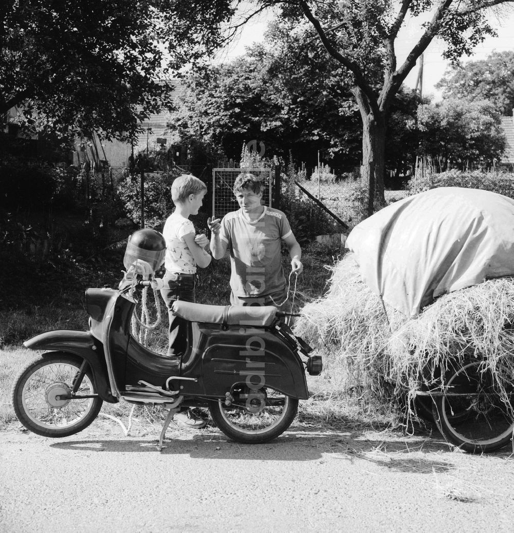 DDR-Fotoarchiv: Schwerin - Vater mit Sohn und ein Motorrad der Marke Simson Schwalbe mit Anhänger in Schwerin in Mecklenburg-Vorpommern in der DDR