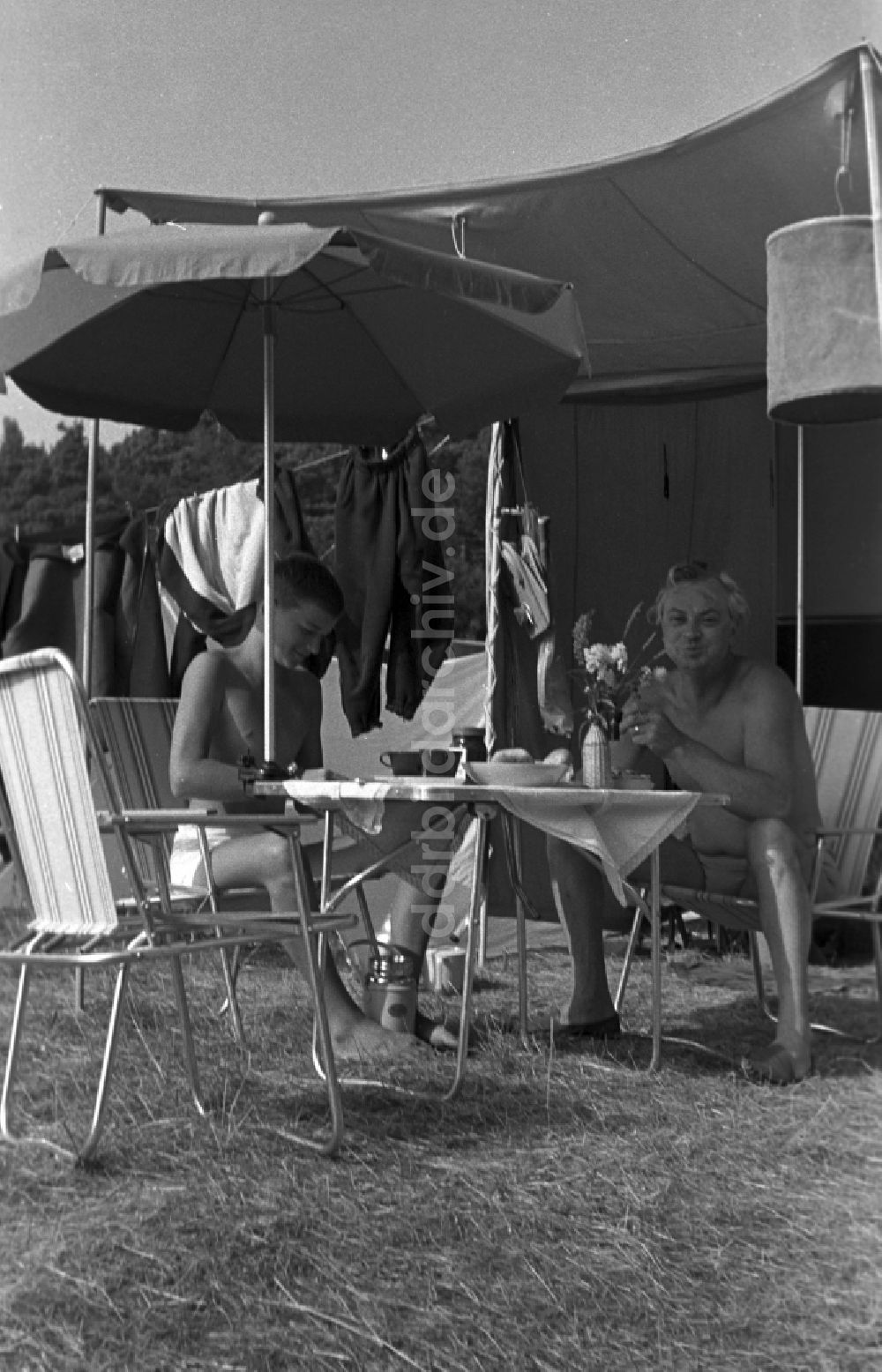 Neuruppin OT Stendenitz: Vater und Sohn sitzen auf Campingstühlen unter einem Vorzelt auf dem Campingplatz am Tornowsee in Brandenburg