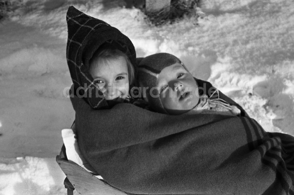 DDR-Fotoarchiv: Merseburg - Zwei Kinder liegen auf einem Schlitten in Merseburg in Sachsen-Anhalt in Deutschland