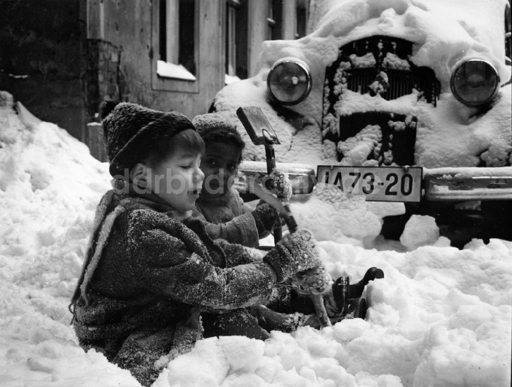 DDR-Fotoarchiv: Berlin - Zwei Kinder sitzen am Strassenrand im Schnee in Berlin, der ehemaligen Hauptstadt der DDR, Deutsche Demokratische Republik