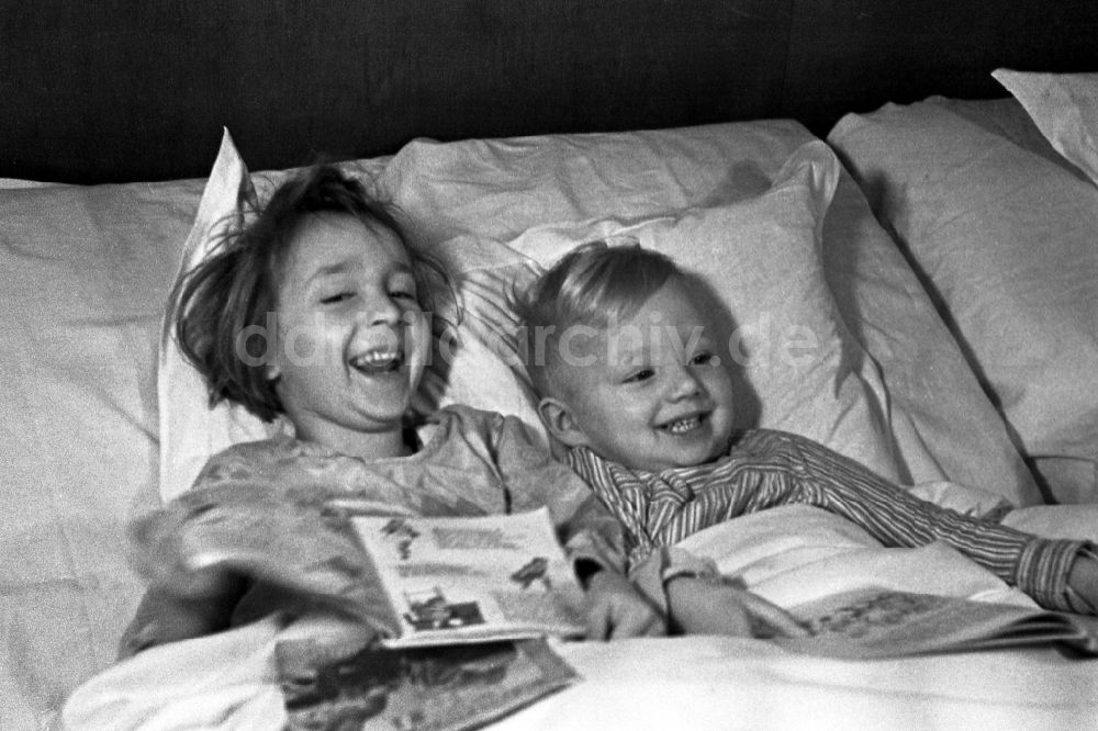 DDR-Bildarchiv: Merseburg - Zwei kleine Kinder liegen lachend im Bett der Eltern in Merseburg im Bundesland Sachsen-Anhalt in Deutschland