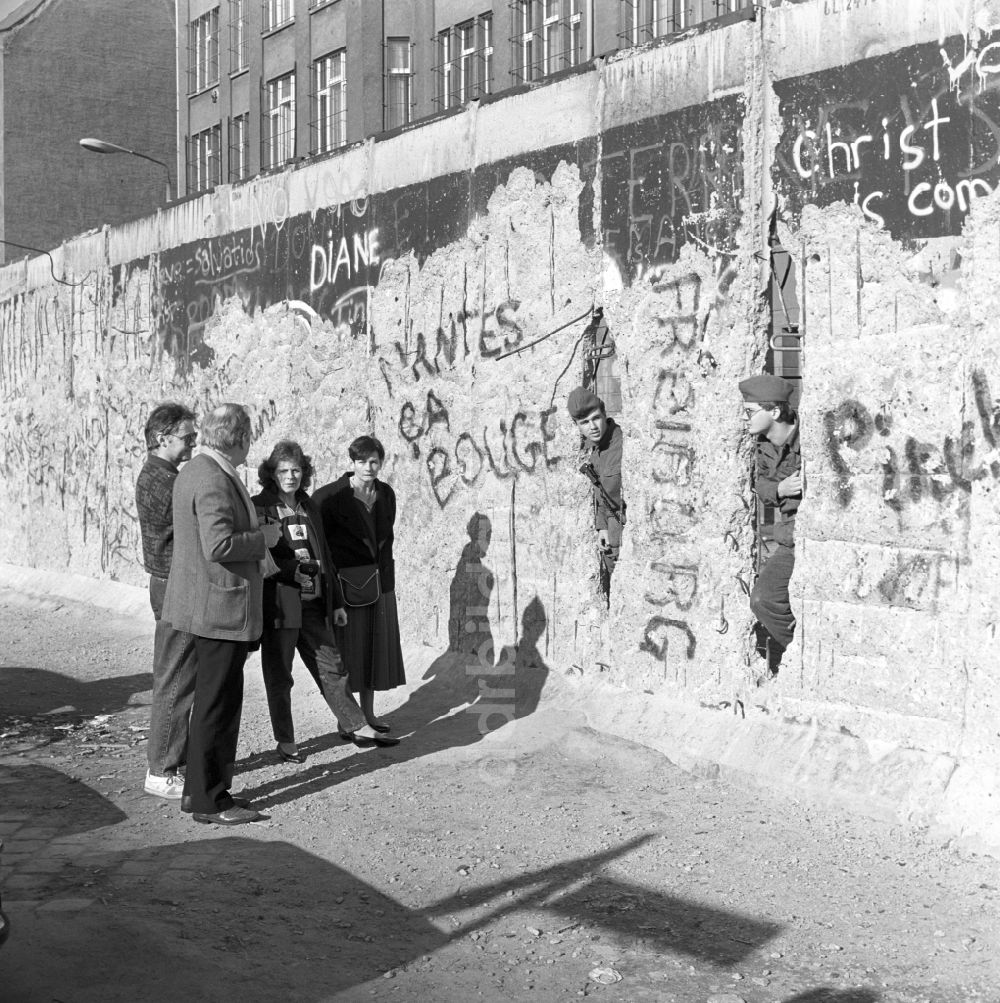 DDR-Fotoarchiv: Berlin - Zwei Soldaten der Grenztruppen der DDR schauen durch ein Loch in der Berliner Mauer in Berlin