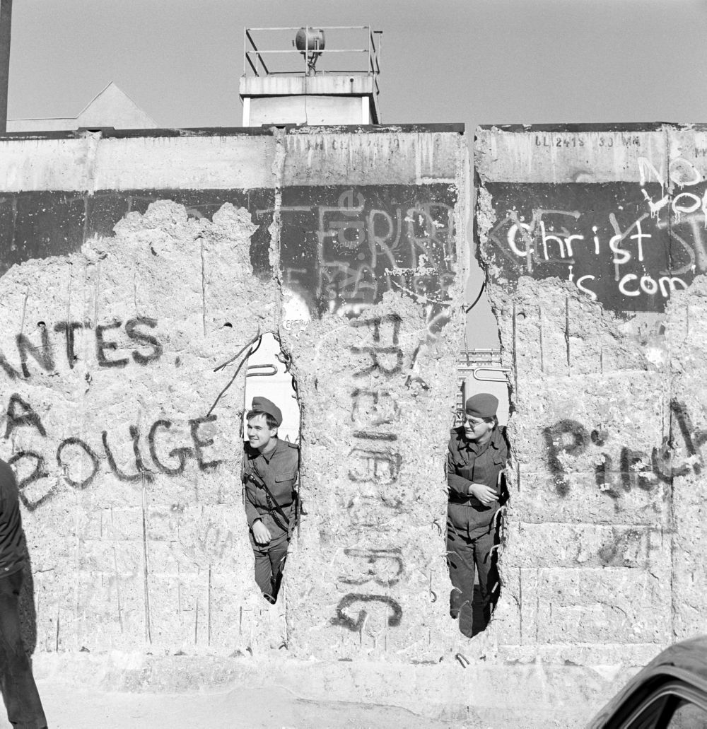 DDR-Fotoarchiv: Berlin - Zwei Soldaten der Grenztruppen der DDR schauen durch ein Loch in der Berliner Mauer in Berlin